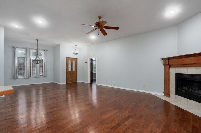 unfurnished living room with recessed lighting, wood finished floors, ceiling fan with notable chandelier, and a tile fireplace