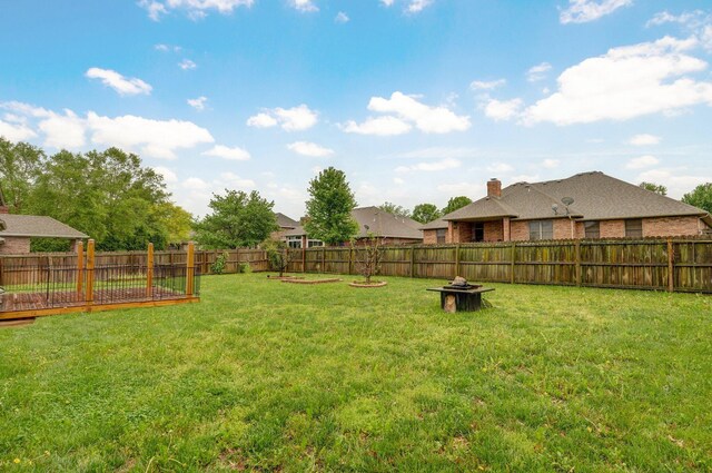 view of yard featuring a fenced backyard and a fire pit