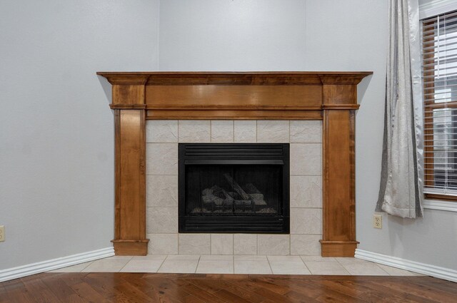 details with baseboards, decorative columns, a tile fireplace, and wood finished floors