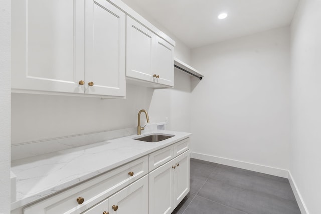 laundry area with dark tile patterned flooring, recessed lighting, baseboards, and a sink