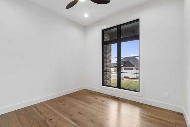 unfurnished room featuring a ceiling fan, baseboards, visible vents, and wood finished floors
