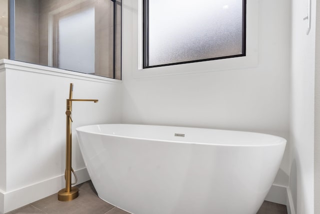 bathroom featuring baseboards, tile patterned flooring, and a soaking tub