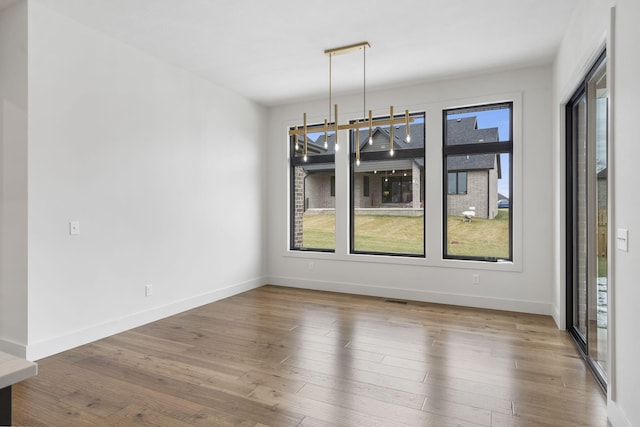 unfurnished dining area featuring baseboards, hardwood / wood-style floors, and visible vents