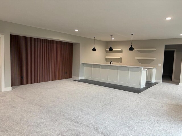 unfurnished living room with recessed lighting, baseboards, dark colored carpet, and a sink