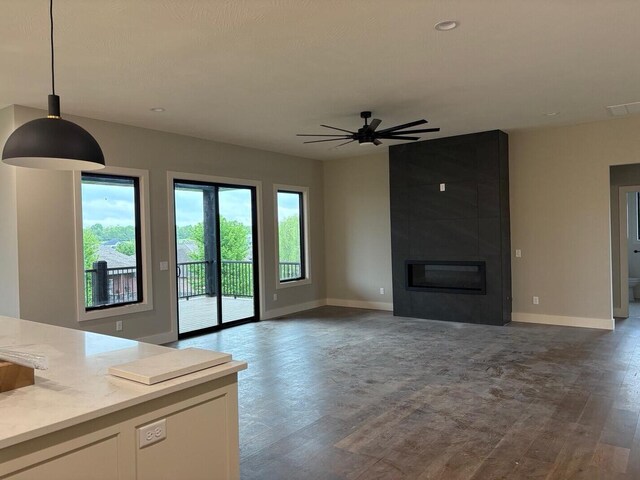 unfurnished living room featuring baseboards, a large fireplace, and wood finished floors