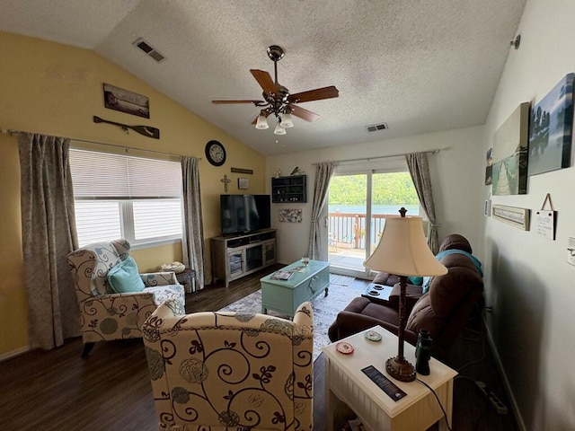 living room with a ceiling fan, vaulted ceiling, dark wood finished floors, and visible vents