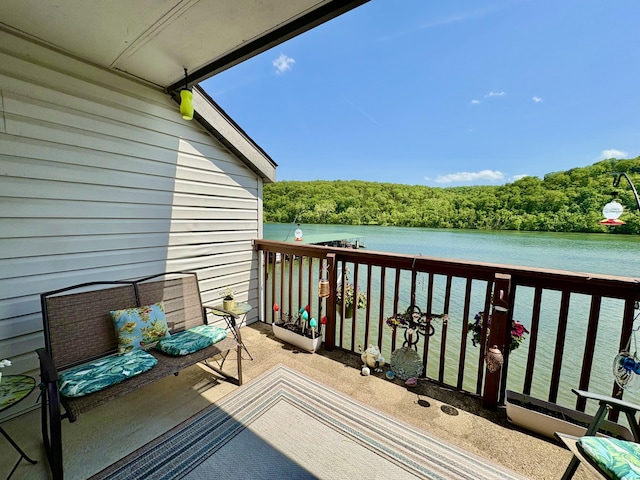 balcony featuring a water view and a wooded view
