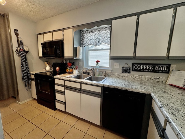 kitchen with light tile patterned flooring, light countertops, a textured ceiling, a sink, and black appliances