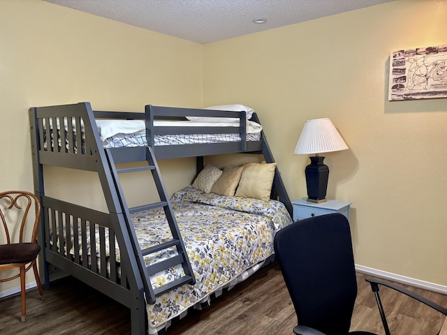 bedroom with baseboards, a textured ceiling, and wood finished floors