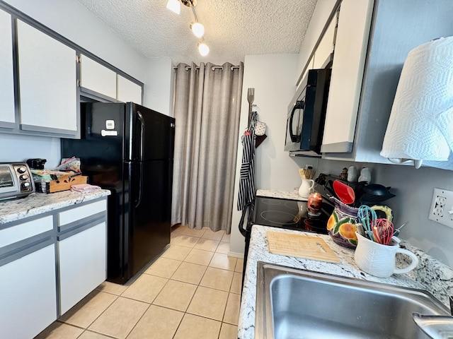 kitchen with light countertops, white cabinetry, a sink, light tile patterned floors, and black appliances