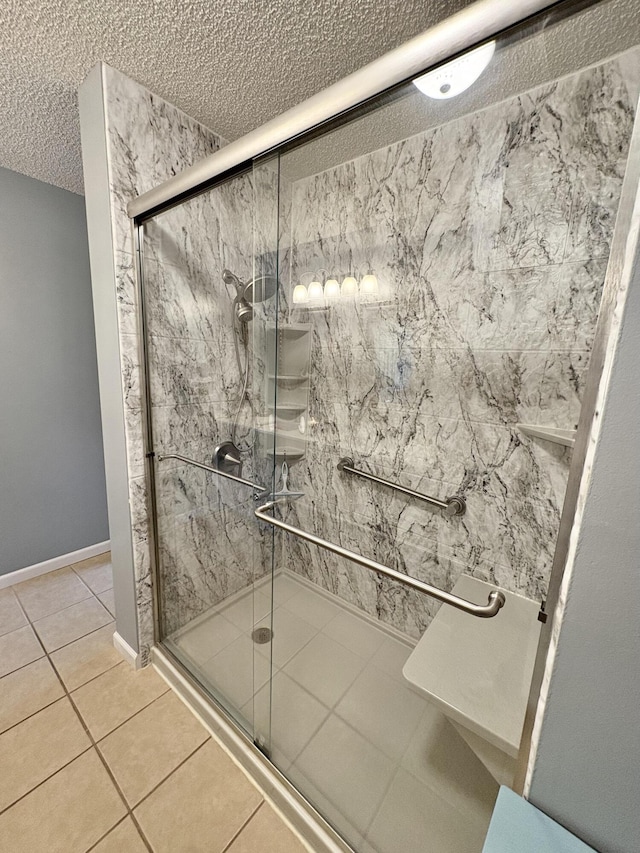bathroom with tile patterned flooring, a textured ceiling, baseboards, and a shower stall