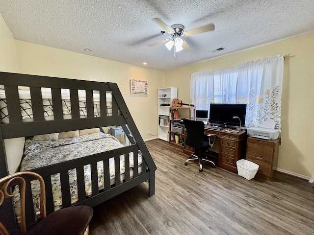 bedroom with a textured ceiling, baseboards, visible vents, and wood finished floors