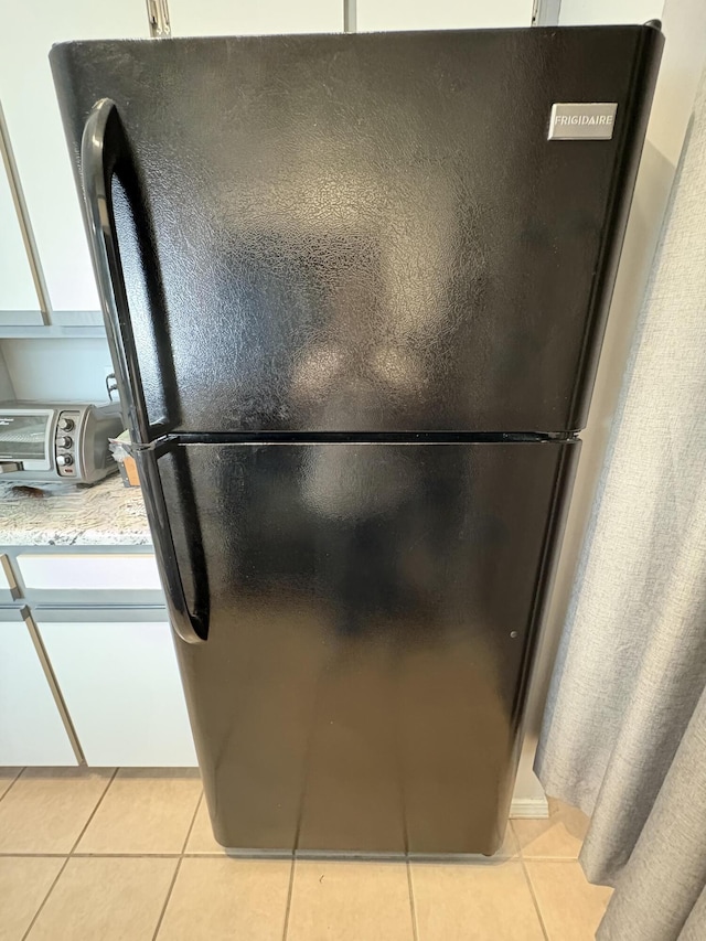 interior details featuring a toaster, light stone counters, and freestanding refrigerator