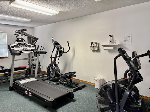 workout area with carpet floors, a textured ceiling, and baseboards