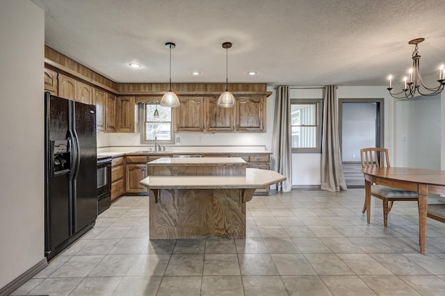 kitchen featuring brown cabinets, black fridge, light countertops, a chandelier, and a center island