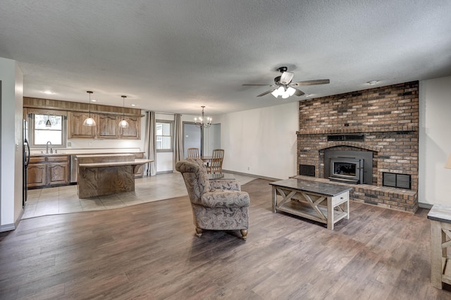 living area featuring light wood-style floors, a textured ceiling, ceiling fan with notable chandelier, and a healthy amount of sunlight