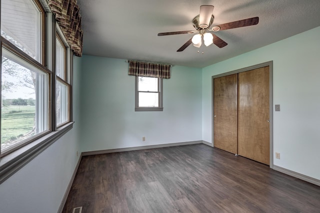 unfurnished bedroom with baseboards, ceiling fan, wood finished floors, and a closet