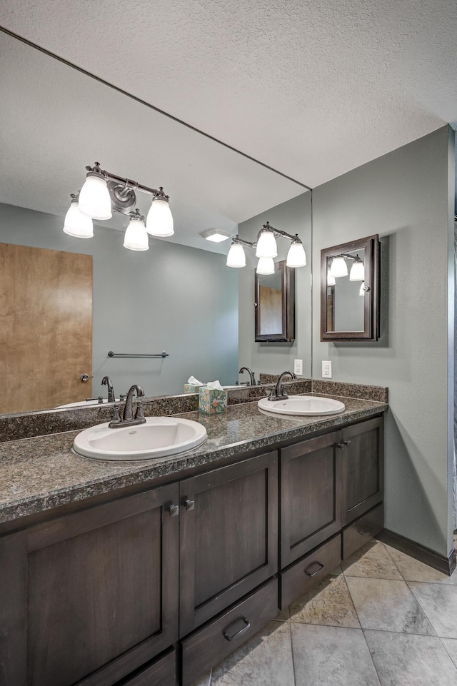 bathroom with double vanity, a textured ceiling, and a sink