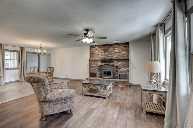 living area featuring baseboards, a textured ceiling, wood finished floors, and ceiling fan with notable chandelier