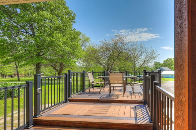 wooden terrace with a lawn and outdoor dining area