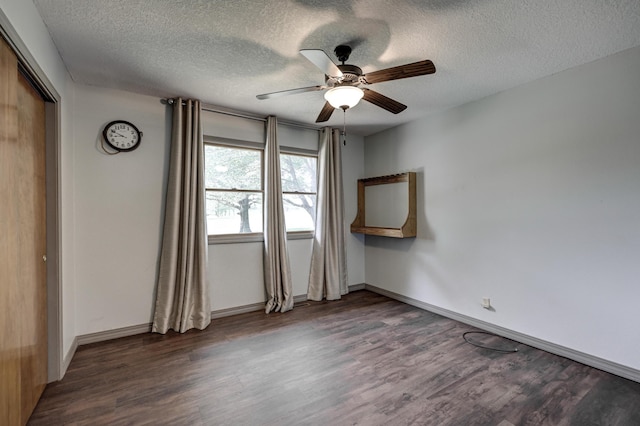 empty room with a textured ceiling, baseboards, a ceiling fan, and wood finished floors