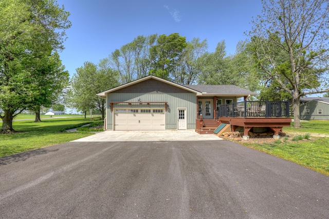 ranch-style home featuring driveway, french doors, a front yard, a wooden deck, and a garage