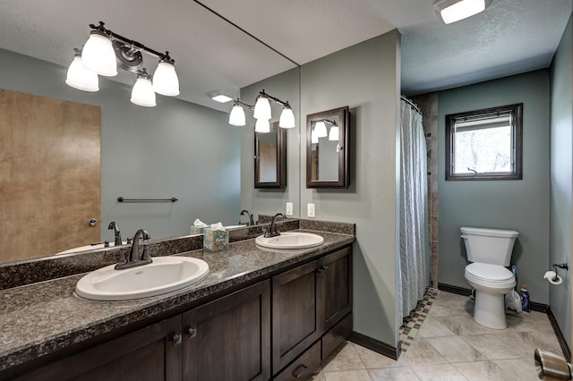 bathroom with double vanity, a sink, baseboards, and toilet