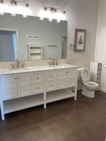 bathroom featuring double vanity, toilet, and a sink