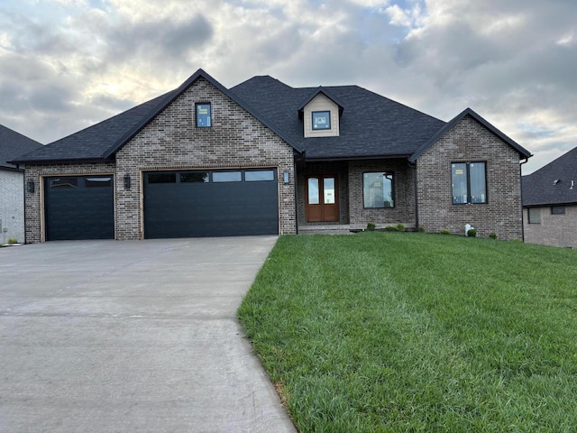 view of front of house featuring driveway, roof with shingles, a front yard, a garage, and brick siding