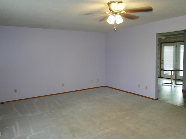 spare room featuring ceiling fan, light carpet, and baseboards