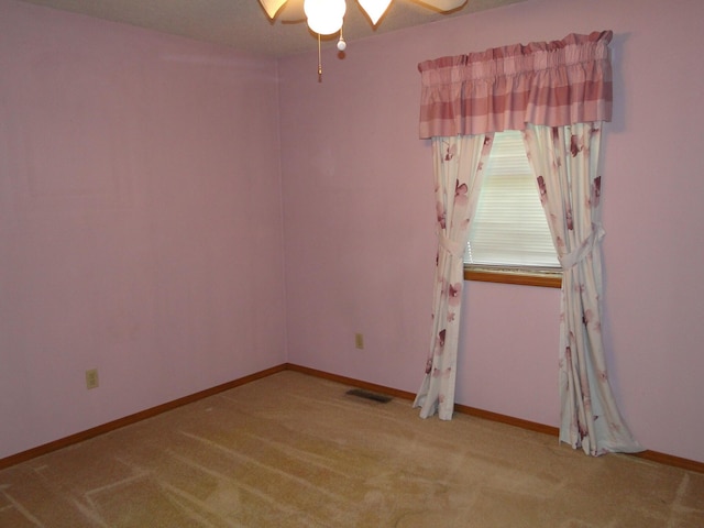 empty room with baseboards, ceiling fan, carpet, and visible vents