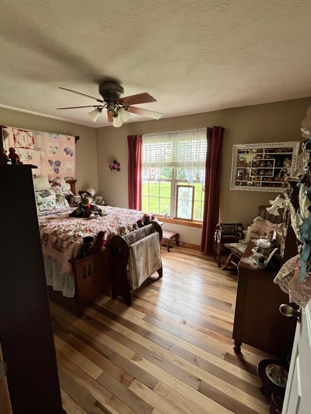 bedroom with ceiling fan, light wood finished floors, and a textured ceiling