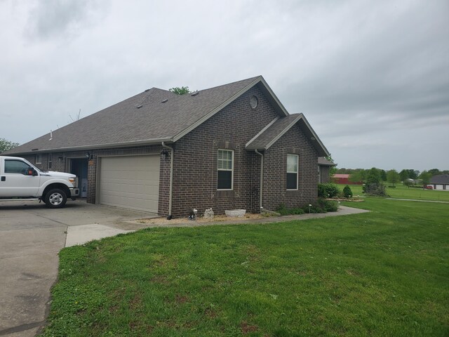 view of property exterior featuring a lawn, roof with shingles, brick siding, concrete driveway, and an attached garage