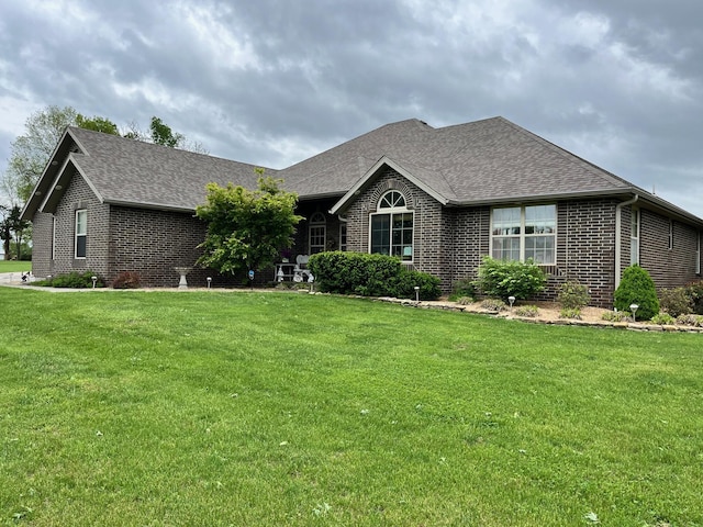 ranch-style home featuring brick siding, a shingled roof, and a front lawn