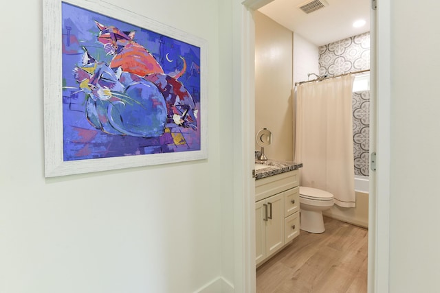 bathroom featuring visible vents, vanity, wood finished floors, toilet, and shower / tub combo