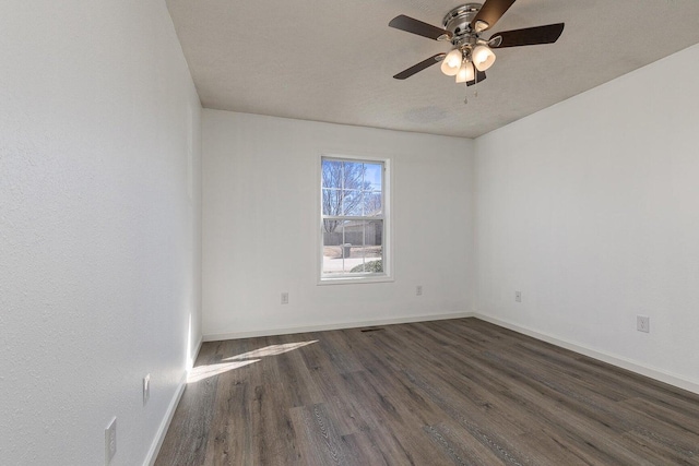 spare room featuring a ceiling fan, baseboards, and dark wood finished floors