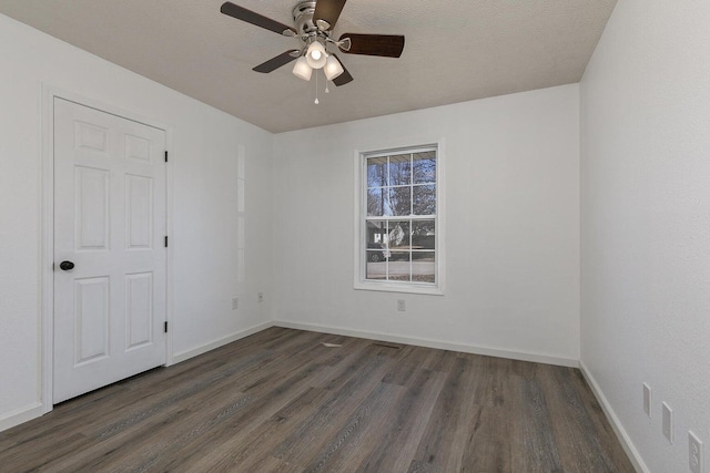 unfurnished room featuring baseboards, dark wood-style flooring, and ceiling fan