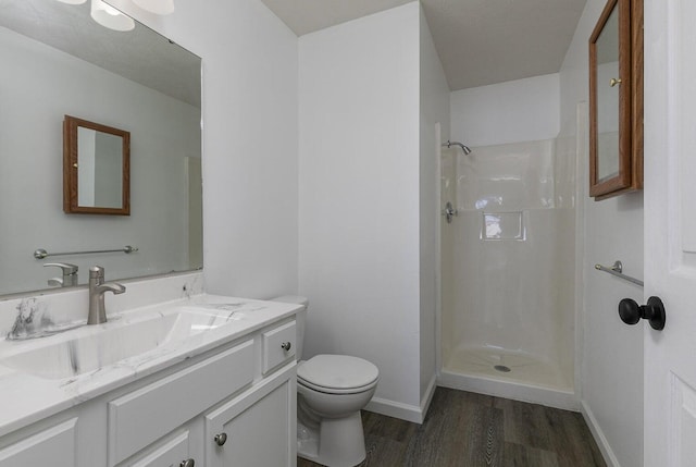 bathroom featuring vanity, wood finished floors, toilet, baseboards, and walk in shower