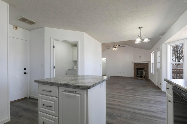 kitchen with visible vents, wood finished floors, dishwasher, ceiling fan with notable chandelier, and washer / dryer