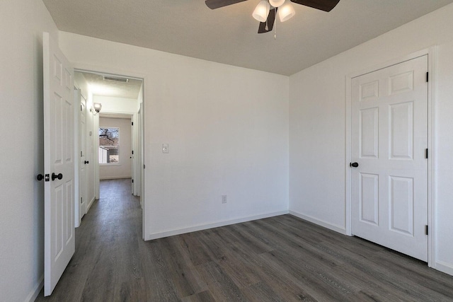 unfurnished bedroom with baseboards, a ceiling fan, dark wood finished floors, and visible vents