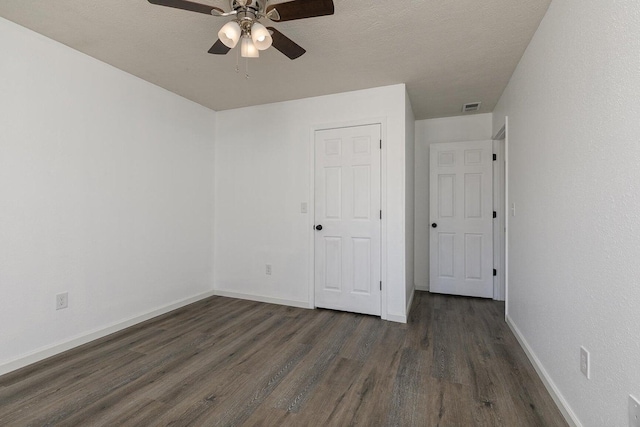 unfurnished bedroom with baseboards, ceiling fan, dark wood-style flooring, and visible vents