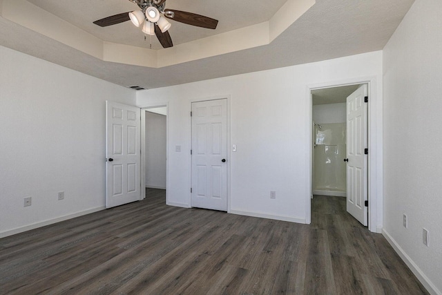 unfurnished bedroom with dark wood-type flooring, baseboards, ensuite bath, and visible vents