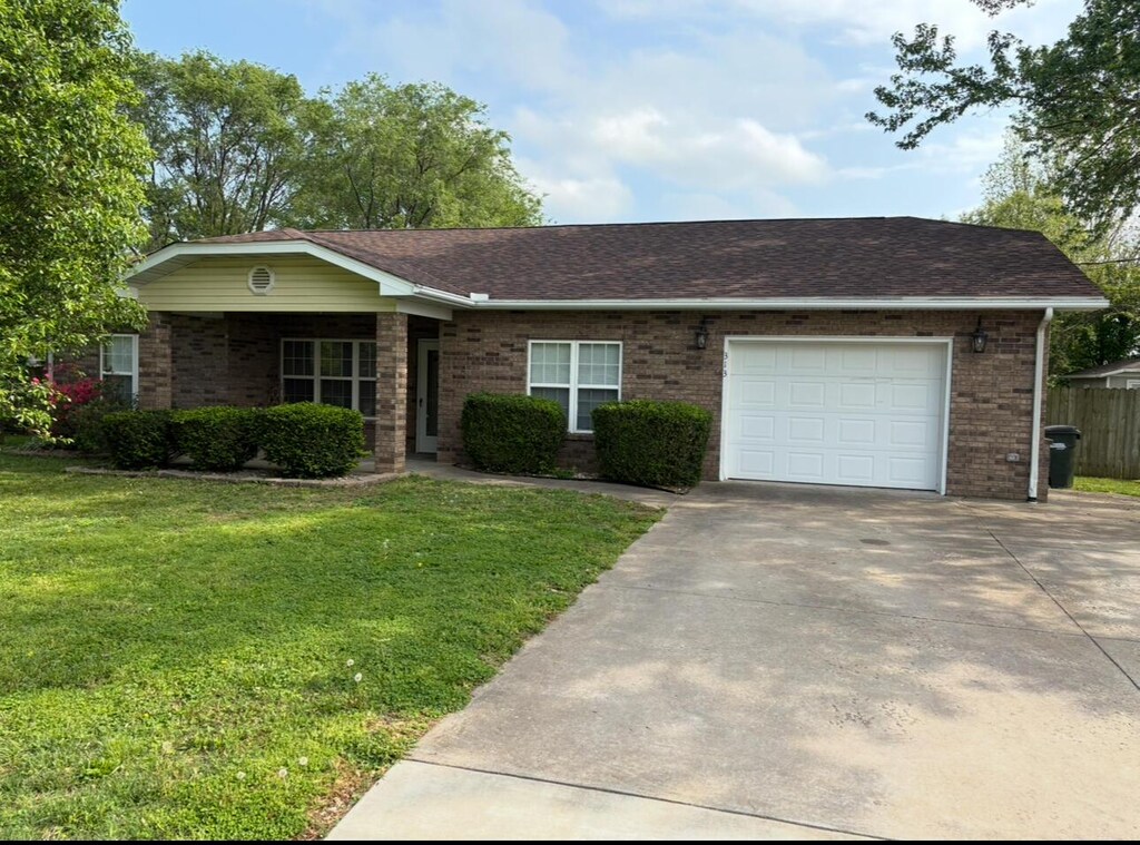 313 W Phelps Ave, Pierce City, MO 65723 - single story home featuring a garage, driveway, a front lawn, and brick siding