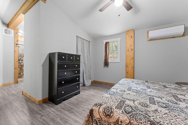bedroom featuring an AC wall unit, lofted ceiling, wood finished floors, and visible vents