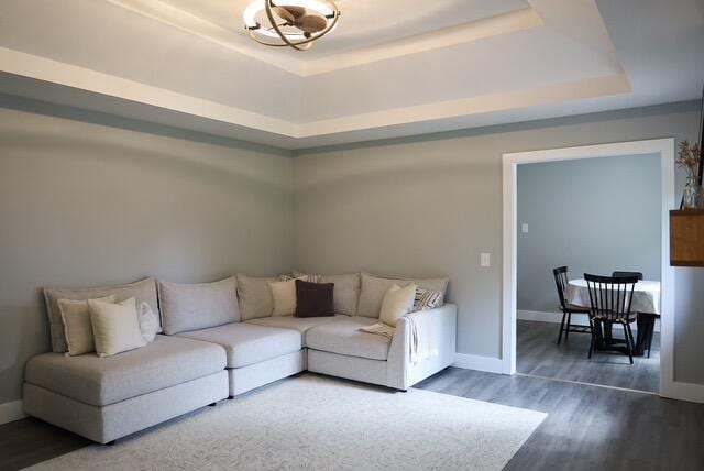 living room with baseboards, a raised ceiling, and wood finished floors