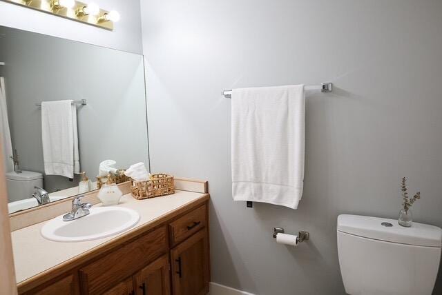 bathroom with vanity, baseboards, and toilet