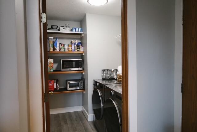 washroom featuring laundry area, dark wood-style flooring, a toaster, baseboards, and washer and dryer