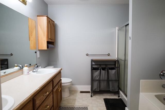 full bathroom with double vanity, visible vents, a stall shower, baseboards, and toilet
