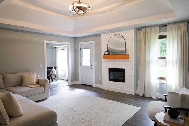 living room with a raised ceiling, a healthy amount of sunlight, and a fireplace