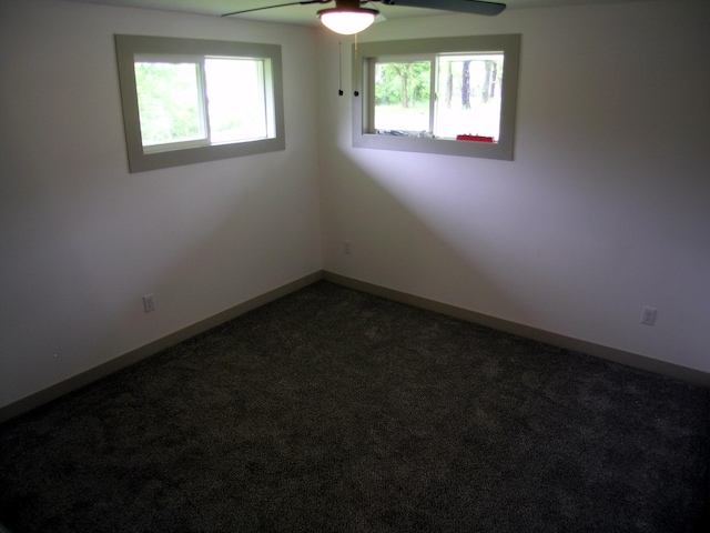 spare room with a ceiling fan, baseboards, and dark carpet